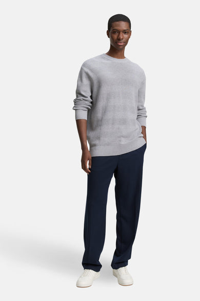 Sweat-shirt gris à col rond de TOM TAILOR, avec des manches longues et associé à un pantalon bleu marine et des baskets blanches.