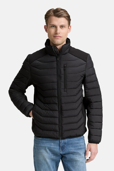 Manteau court noir de Tom Tailor, avec fermeture éclair et détails en tissu duaté, porté sur un jean bleu.