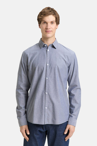 Man draagt blauw overhemd met lange mouwen.