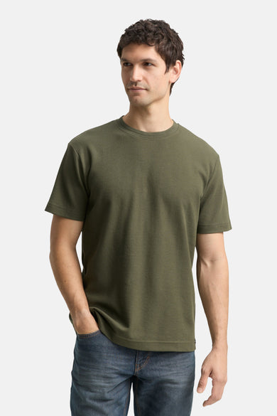 T-shirt vert avec manches courtes de TOM TAILOR, porté avec un jeans bleu et des baskets blanches.