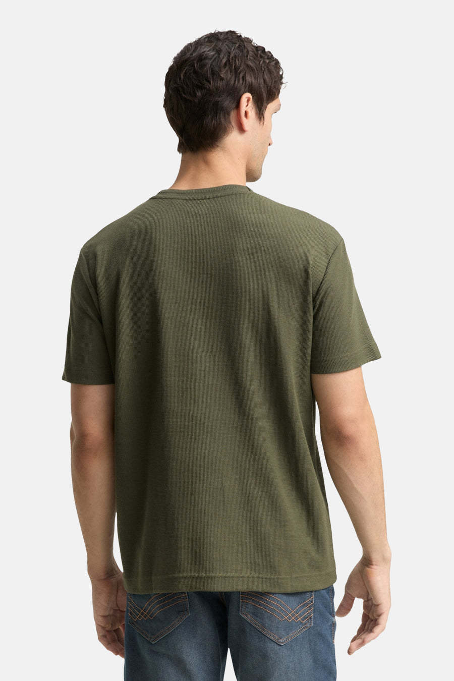 Achterkant van een man in een olijfgroen thermisch t-shirt en jeans.