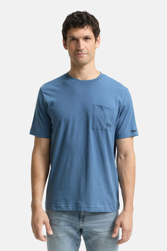 T-shirt bleu à manches courtes de TOM TAILOR, avec une poche devant et des jeans bleus clairs et des chaussures blanches.