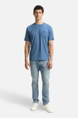 Blauw T-shirt met korte mouwen van TOM TAILOR, met borstzak en lichtblauwe jeans en witte schoenen.
