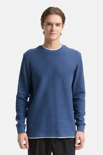 Man met een blauw, geribbeld shirt.