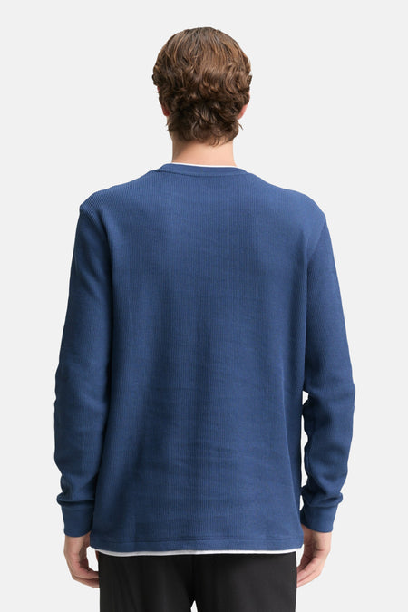 Achterkant van een blauwe trui met lange mouwen.
