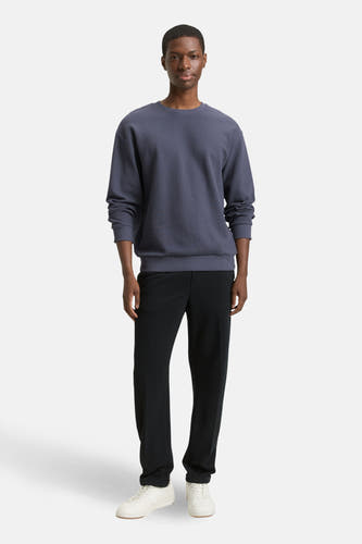 Blauwe sweater met ronde hals van TOM TAILOR, gecombineerd met zwarte pantalon en witte sneakers.

