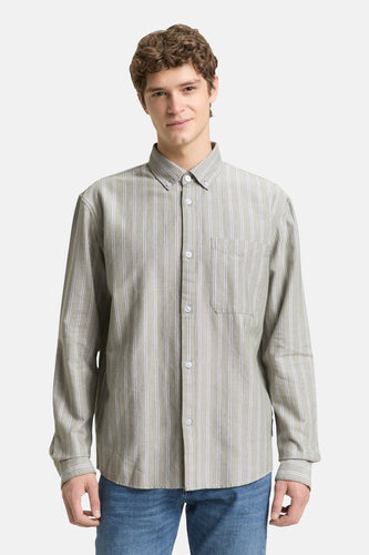 Man in gestreept overhemd, blauwe jeans.
