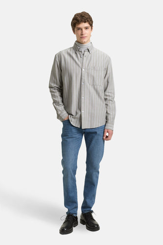 Een man in jeans en een gestreept overhemd.