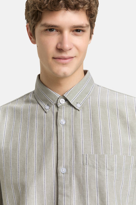 Jonge man met een gestreept overhemd in kaki.