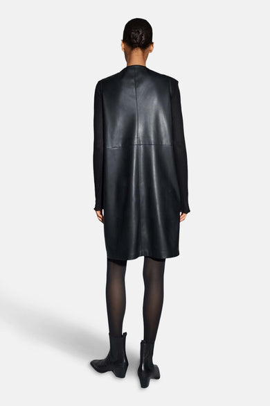 Zwarte jurk met korte mouwen van OPUS, gezien van achteren, met lange mouwen shirt en zwarte panty en laarzen.
