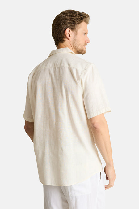 Chemise écru à manches courtes de TOM TAILOR, avec une texture subtilement rayée, portée dans le dos par un homme en pantalon blanc.