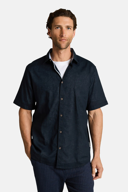 Chemise bleue à manches courtes de TOM TAILOR, portée sur un t-shirt blanc et un pantalon rayé.