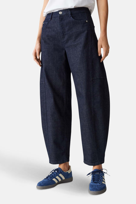 Donkerblauwe jeans, blauwe Adidas sneakers.