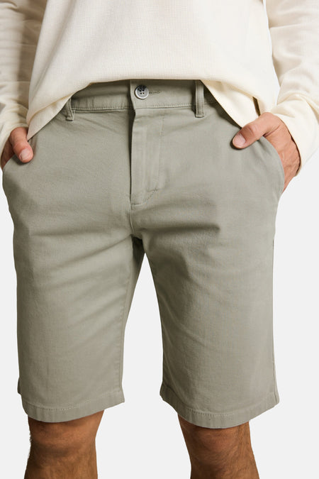 Shorts vert clair TOM TAILOR en sergé, avec fermeture à boutons et passants de ceinture, portés avec un t-shirt crème en nid d'abeille.