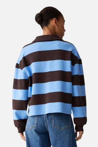 Achterkant van een model in een blauw en bruin gestreepte trui en blauwe jeans.