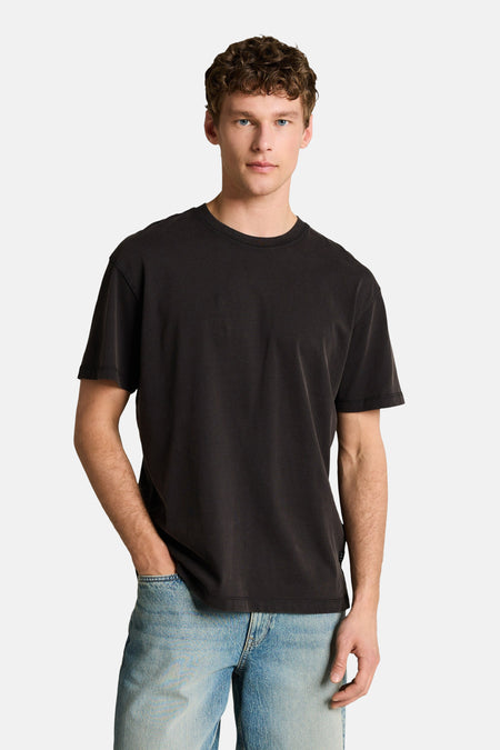 T-shirt noir à manches courtes de TOM TAILOR, porté avec un short en jean et des baskets de couleur crème.