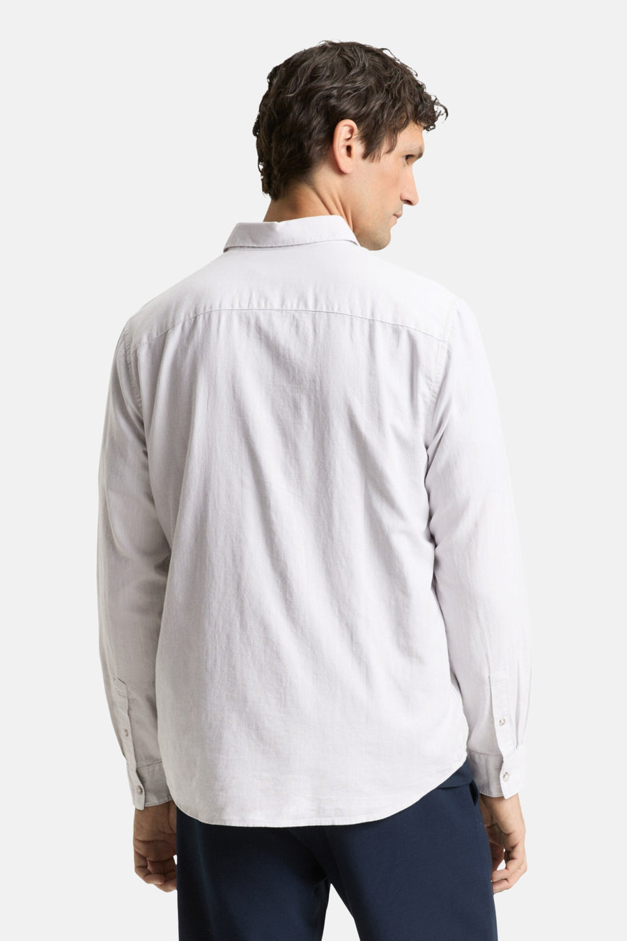 Man met een grijs overhemd van achteren.
