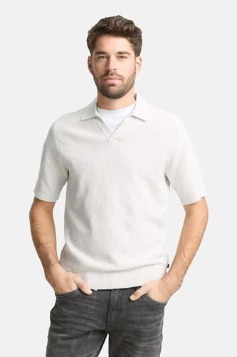 Polo écru à manches courtes de Tom Tailor, avec une texture subtile et combinée avec un jean foncé et des baskets blanches.