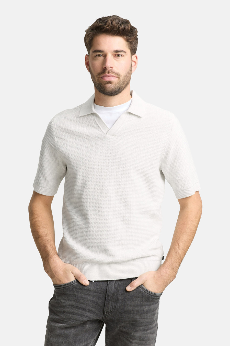 Polo écru à manches courtes de Tom Tailor, avec une texture subtile et combinée avec un jean foncé et des baskets blanches.