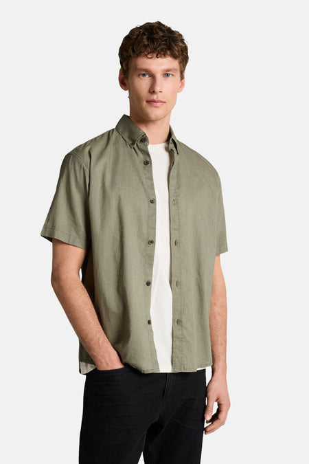 Chemise verte à manches courtes de TOM TAILOR, portée sur un t-shirt blanc et un pantalon noir.