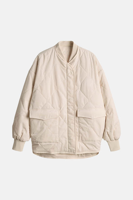 Manteau court beige d'OPUS, avec un matelassage en losange et deux poches sur le devant.