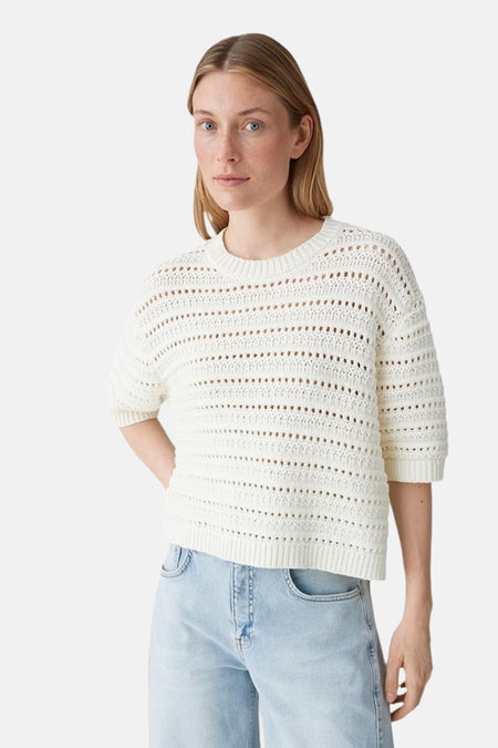 Pull écru à col rond OPUS, avec détails en maille ajourée, combiné avec un jean bleu clair et des chaussures plates.