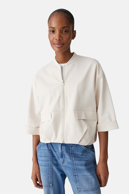 Veste courte de couleur écru d'OPUS, avec une fermeture à glissière et des poches latérales à l'avant.