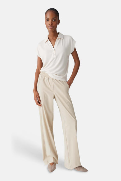 Ecru blouse met korte mouwen van OPUS, met knoopsluiting en gedragen met crèmekleurige pantalon.

