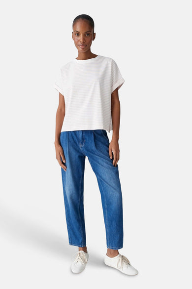 Roze T-shirt van OPUS, met korte mouwen en een subtiel gestreept patroon, gecombineerd met blauwe jeans en witte schoenen.
