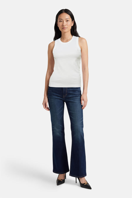 Débardeur blanc OPUS, avec une fine texture côtelée, combiné avec un jean foncé évasé et des escarpins noirs.