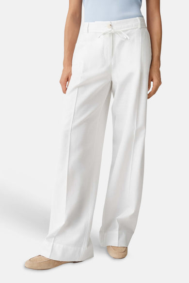 Pantalon écru OPUS à jambes larges, taille élastique et poches latérales, porté avec un haut bleu et des mocassins en daim.