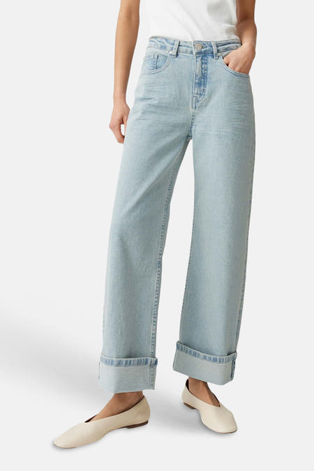 Jean large bleu clair OPUS avec ourlets retroussés, porté avec un haut blanc et des chaussures claires, vue de dos.