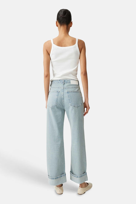 Lichtblauwe wijde jeans van OPUS met omgeslagen zomen, gedragen met een witte top en lichte schoenen, rugaanzicht.