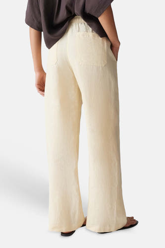 Lichtgele dames seizoensbroek van OPUS met elastische taille, wijde pijpen en achterzakken, vanuit de rug gezien.