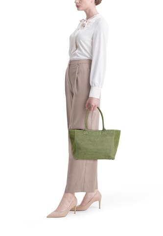 Sac cabas en suède couleur kaki d'Access®, porté par une femme en chemisier blanc et pantalon beige.