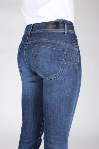 Dos d'une femme en pantalons de travail bleus.