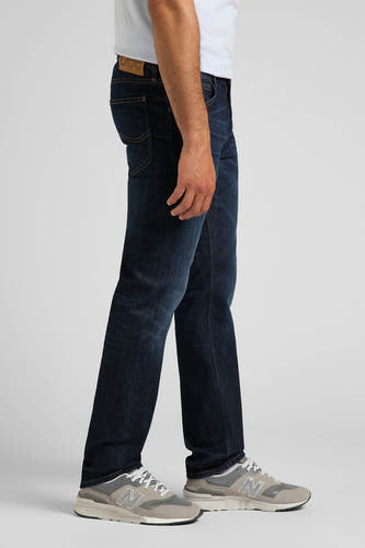 Donkerblauwe straight jeans van Lee, gezien vanaf de zijkant, gedragen met grijze sneakers.
