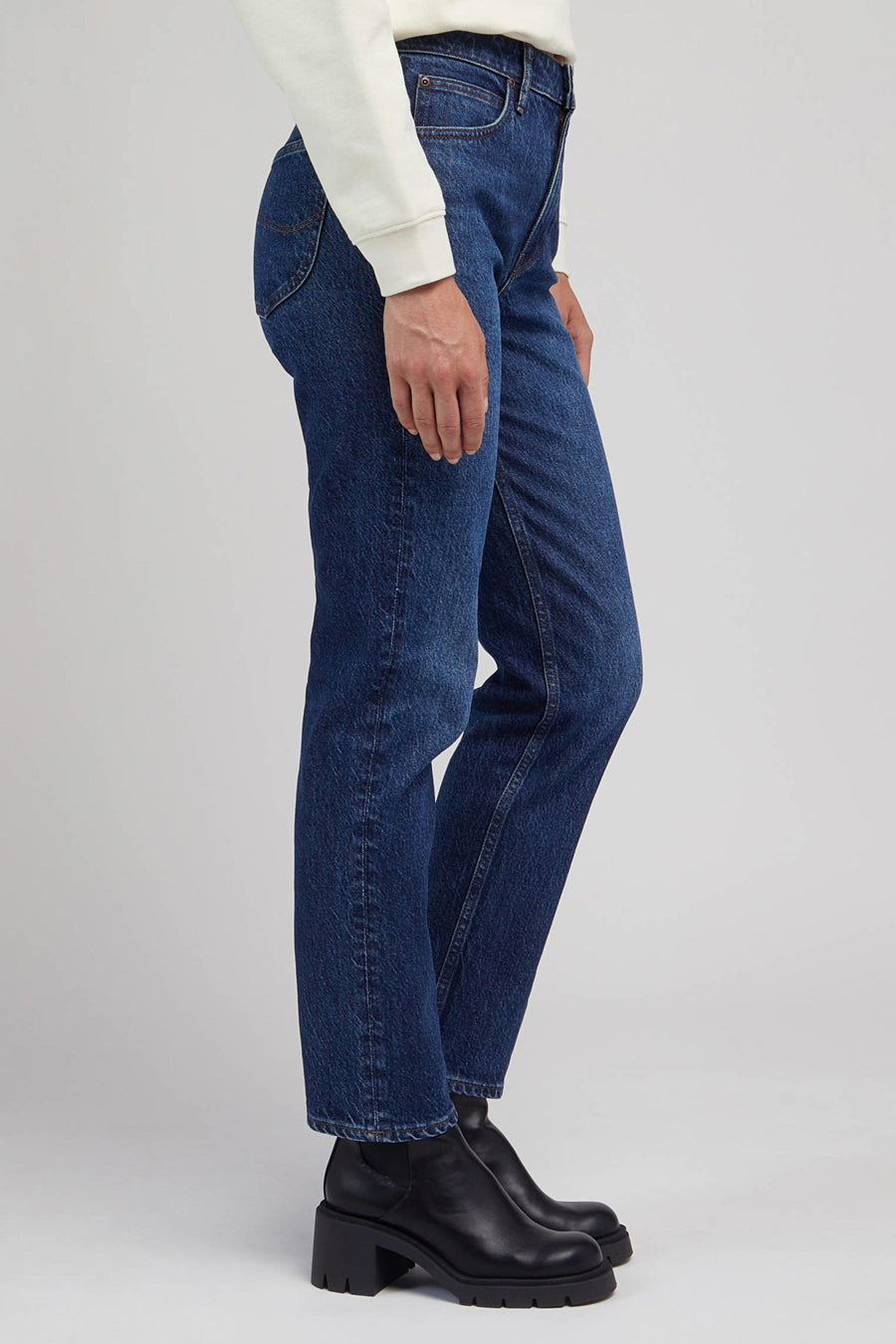 Donkerblauwe jeans, wit sweatshirt, zwarte leren laarzen.