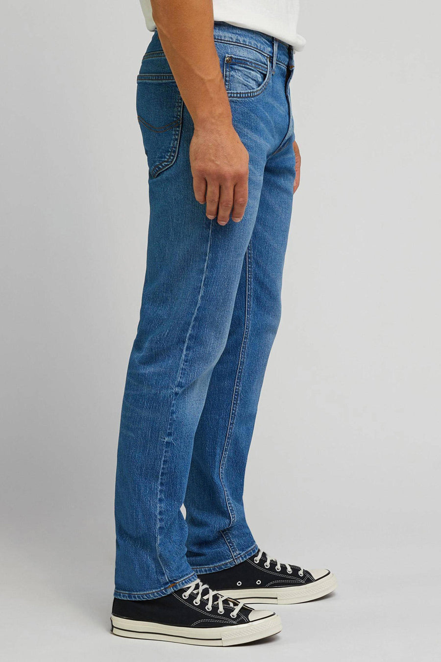 Blauwe straight fit jeans van Lee, te zien in een zijaanzicht, gecombineerd met zwarte canvas schoenen.
