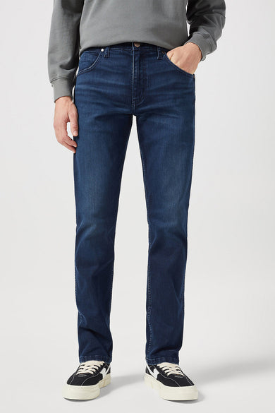 Jean droit bleu foncé Wrangler, dos, avec étiquette de marque en cuir et combiné avec un pull gris et des baskets blanches.