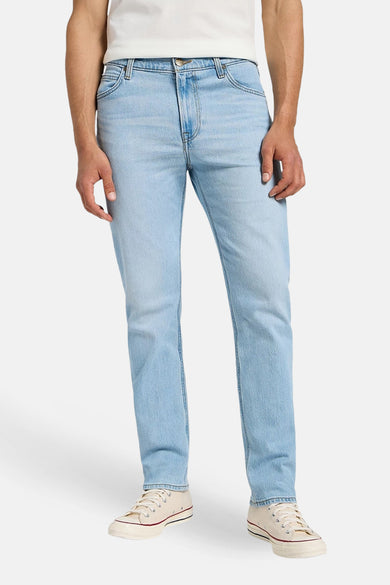 Jean droit bleu clair de Lee, avec un style classique et porté avec des chaussures de canvas crème.