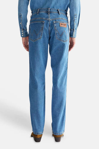 Rechte spijkerbroek van mid-blauw denim van Wrangler, met W-stiksels op de achterzakken en leren patch, van achteren gezien.