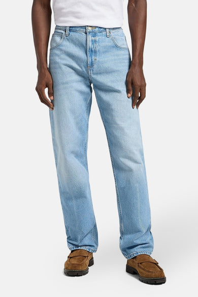 Jean tapered en denim bleu clair de Lee®, porté avec des mocassins en cuir marron et un T-shirt blanc.