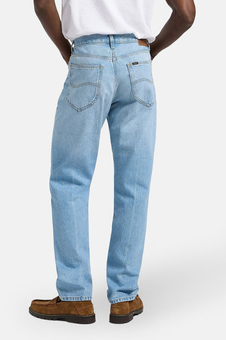 Jean tapered en denim bleu clair de Lee®, avec des chaussures marrons et un t-shirt blanc.