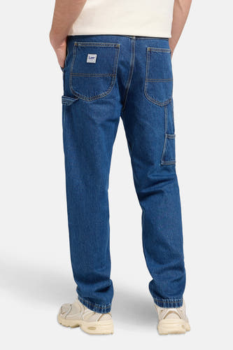 Jean droit de denim bleu moyen de Lee, vu de derrière, avec des chaussures crème.