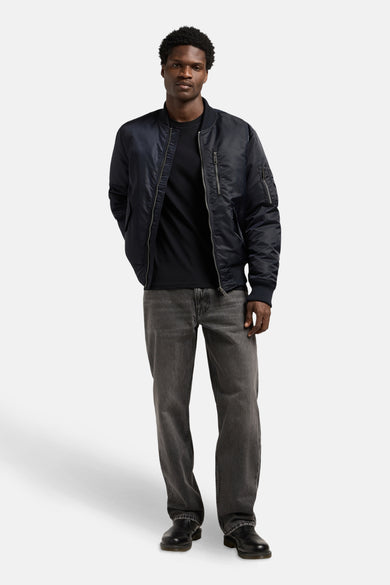 Jean en denim bleu foncé de Lee®, porté avec un t-shirt noir et une veste de vol, associé à des chaussures noires.