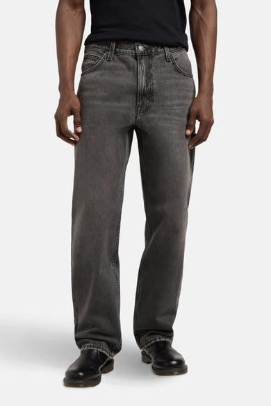 Jean droit en denim gris foncé de Lee®, avec des poches classiques et des chaussures noires.