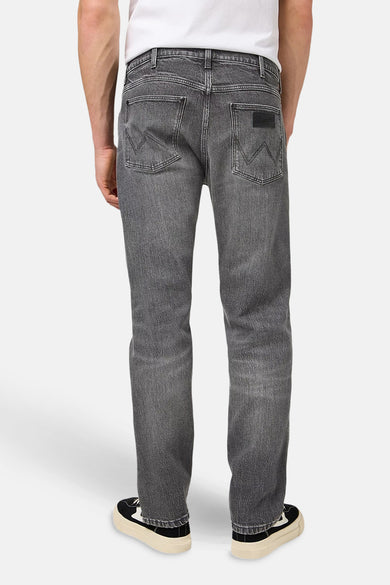 Donkergrijze wide jeans van denim van Wrangler, gezien van achteren, met zwarte schoenen.