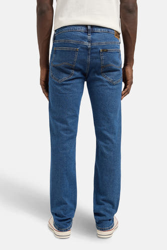 Jean droit en denim bleu de Lee, avec l'arrière visible, doté de petits boutons et de chaussures beige.