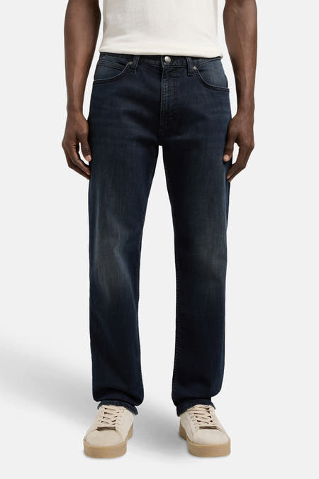 Jean droit en denim bleu de Lee, avec un léger lavage et des chaussures beige.